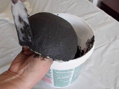 Spreading black papier maché clay onto a bowl mold